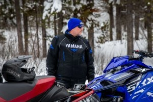 An onlooker looks at 2 snowmobiles.